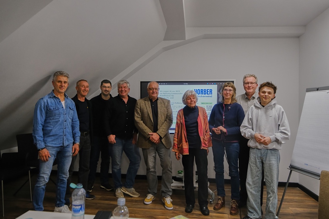 Neun Personen stehen in einem Raum vor einem Bildschirm mit dem Logo von Horber Rückenwind